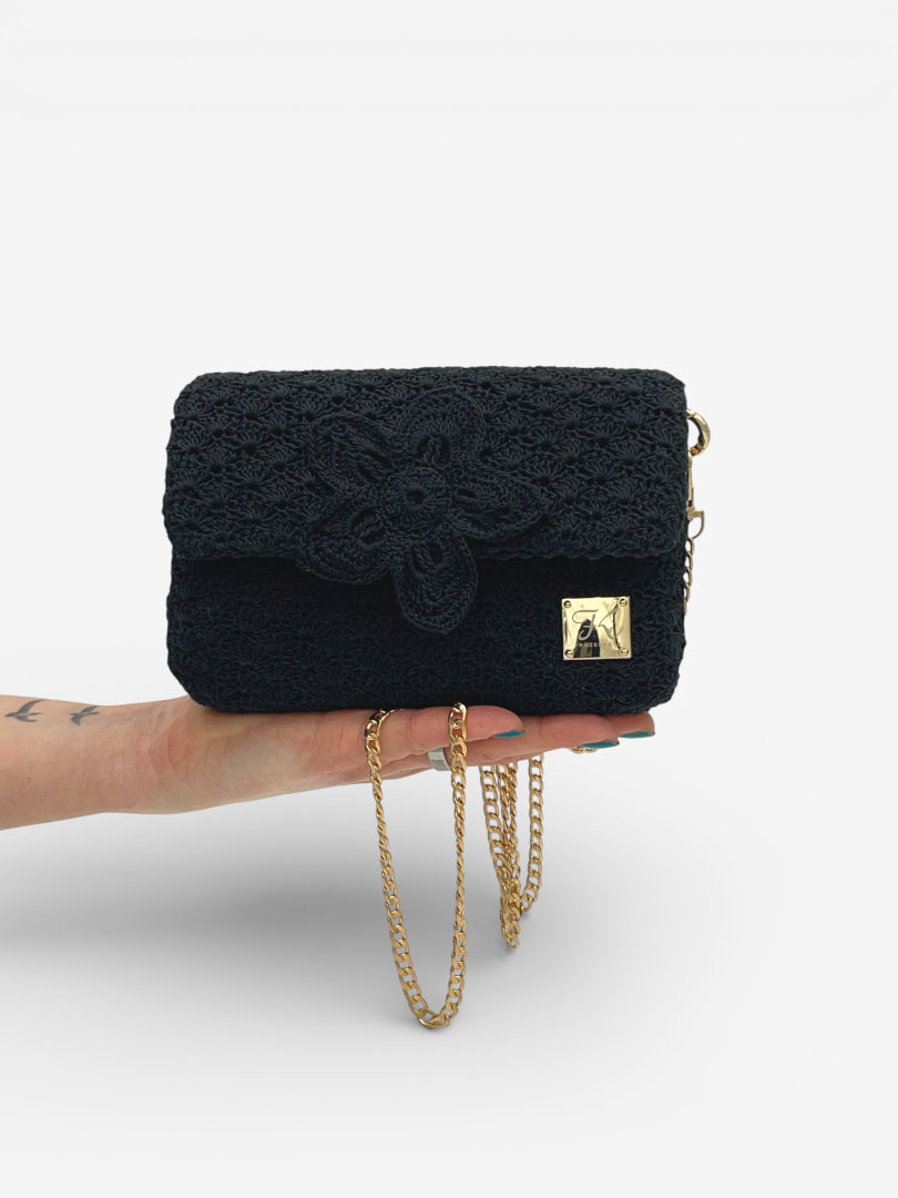 torebka mini z kwiatem czarna trzymana w dłoni